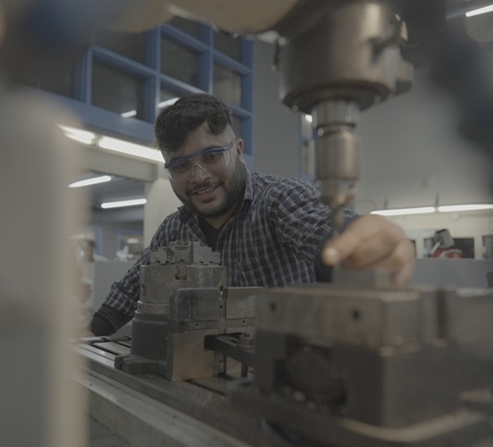 Trades student working in Machine Shop with equipment