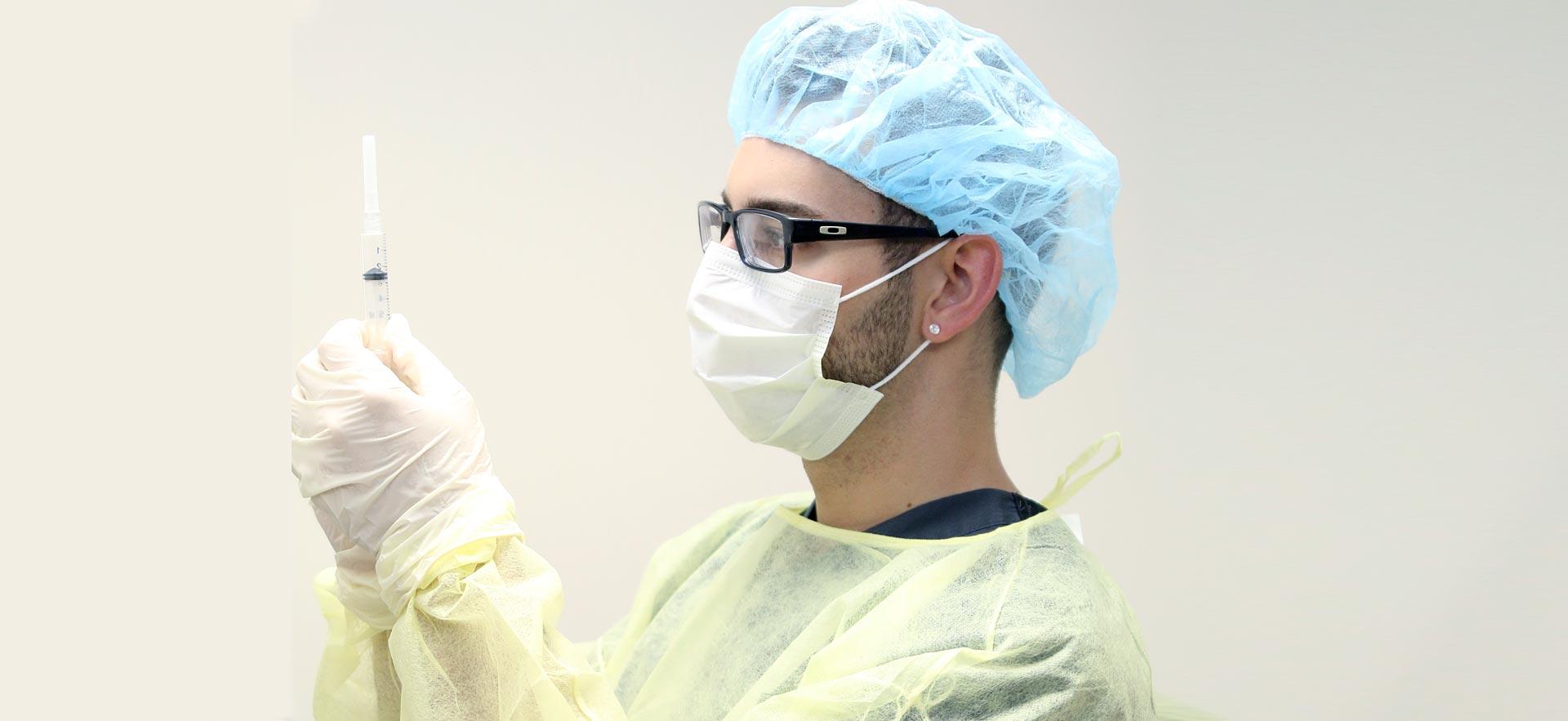 Male student in PPE equipment sterilzes medicine. 