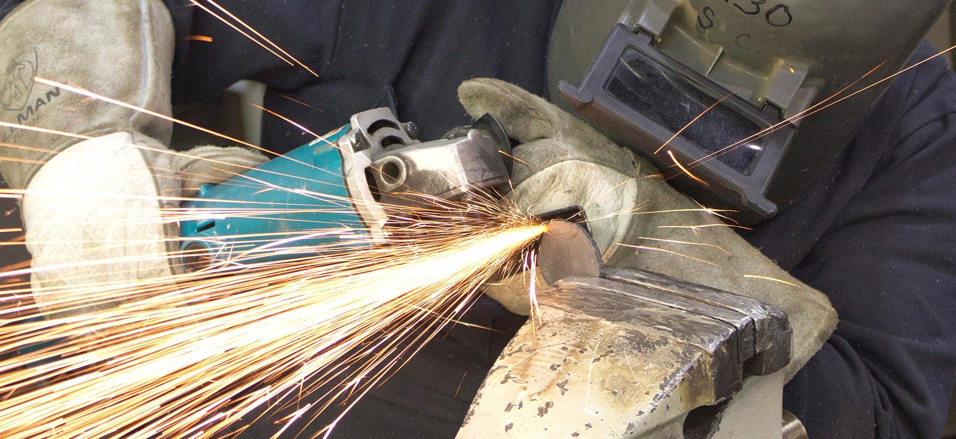 A Metal Fabrication Technician student grinds metal for a class assignment. 