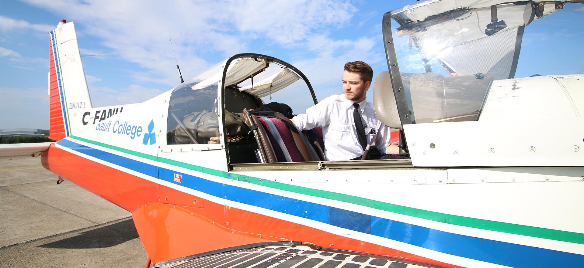 A male aviation student prepares to get out of one of the training planes.