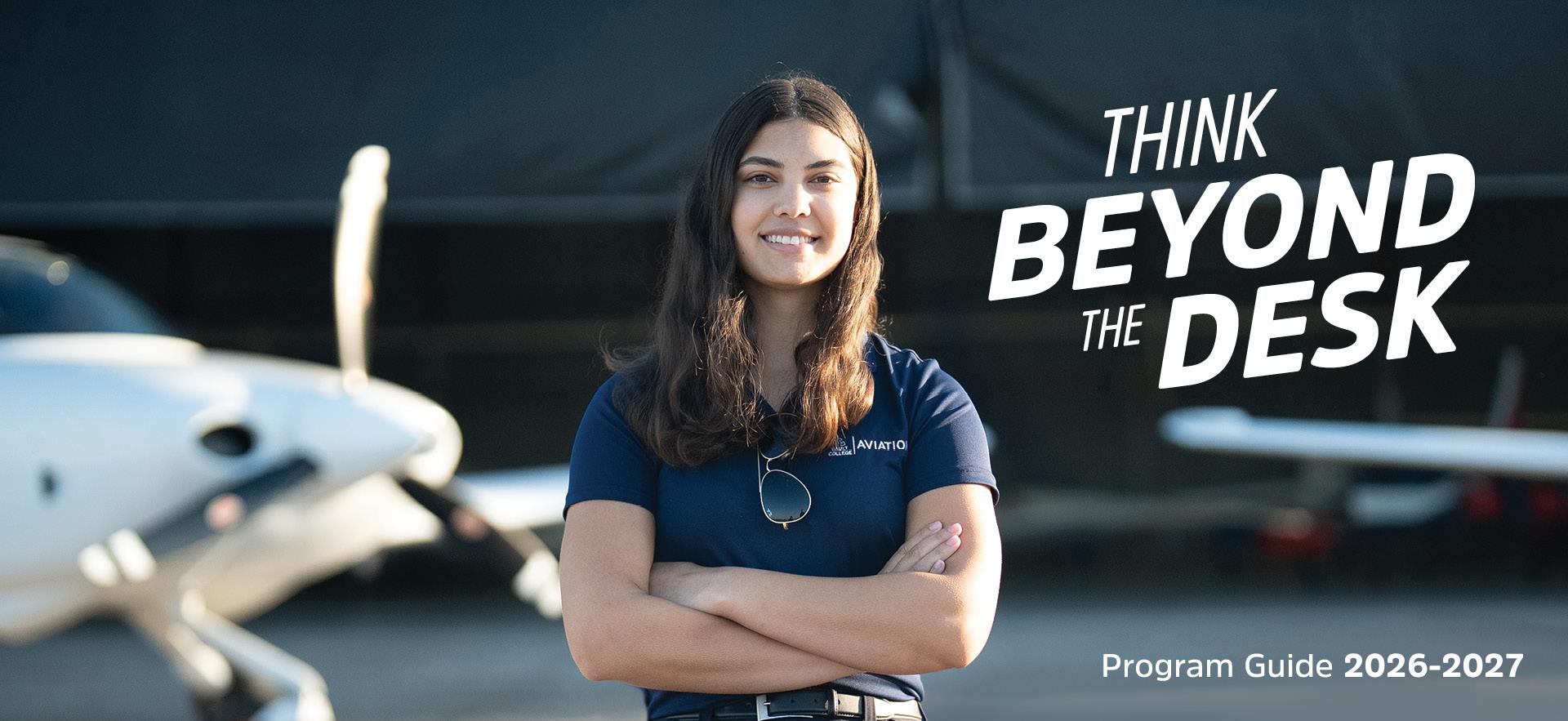 Jaiden Aviation student posed with arms crossing and smiling with planes behind
