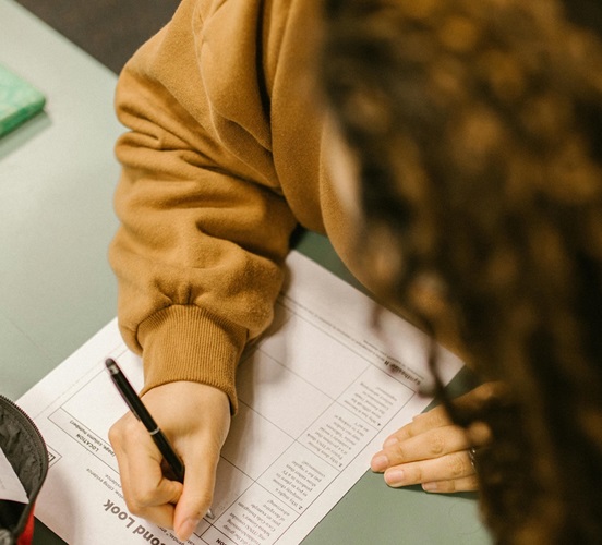 Student looking down and writing at desk