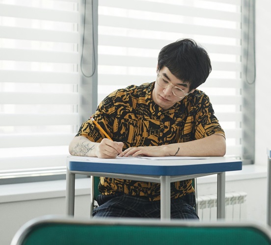 Student in classroom writing on desk