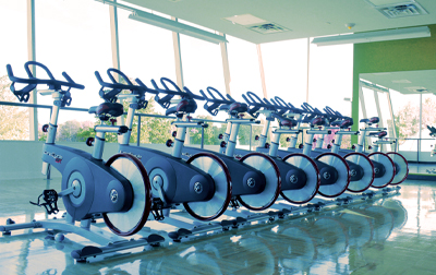 a room in the Fitness Centre with a lineup of exercise bikes facing a large window with mirror to the right