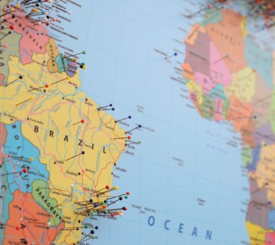 Angled photo of world map with pins inserted in a variety of locations