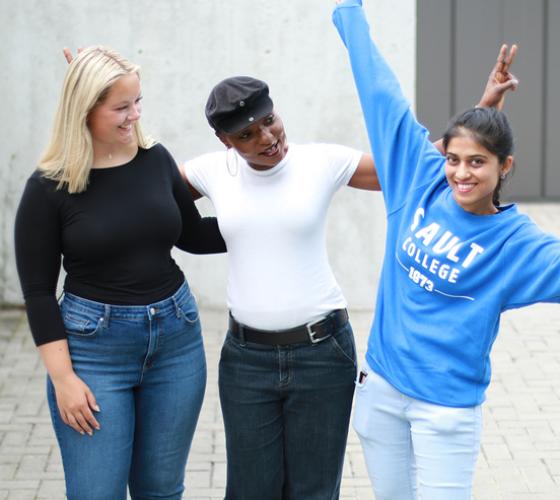Three students having fun outside on campus