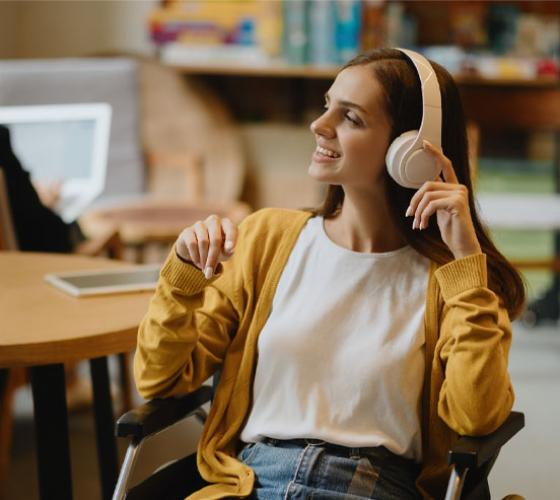 Student seated in wheelchair looking happy with headphones on