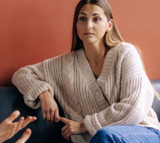 Woman sitting and speaking to someone in a therapy setting