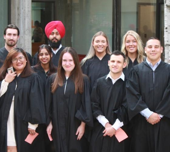Group of graduates in robes posed together outside for convocation