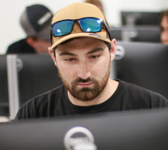 Male student on the computer in a class with students in background