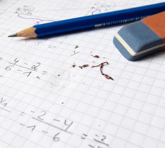 Grid paper shown with equations written and some erasing from pencil and pen on top