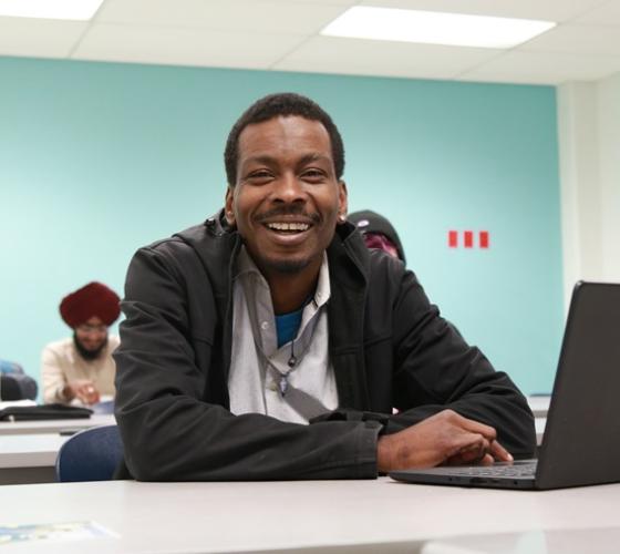 Academic Upgrading student smiling at camera in classroom