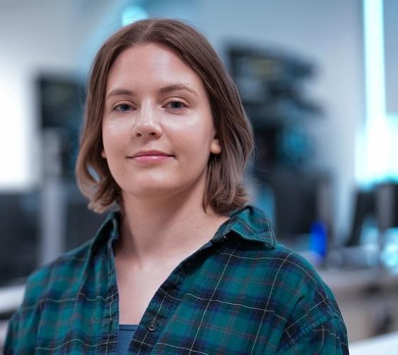 IT student smiling at camera in classroom with computers and networking equipment in background