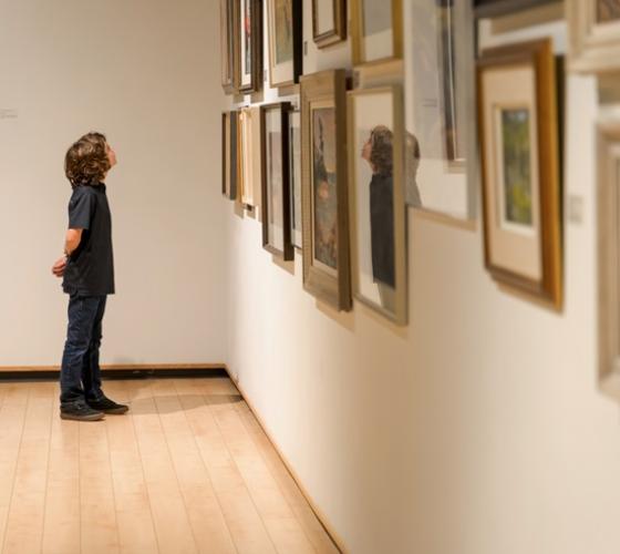 Child looking at artwork on wall at Art Gallery of Algoma