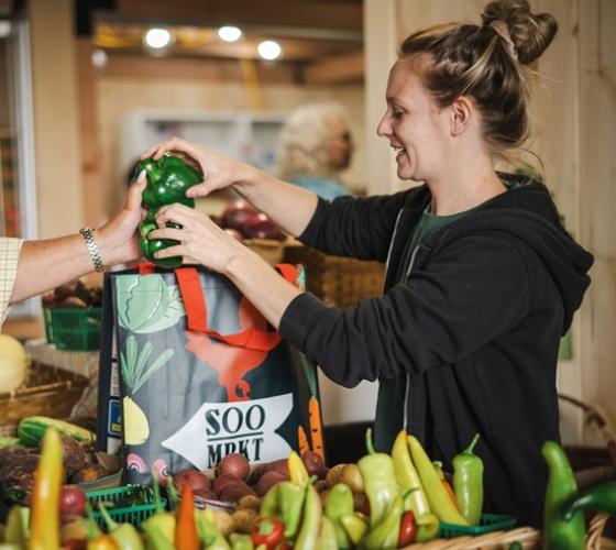 Customer placing fresh produce in reusable bag at Soo Market