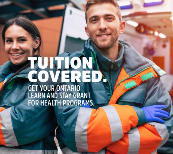 Two paramedics smiling with arms crossed in uniform with ambulance in background
