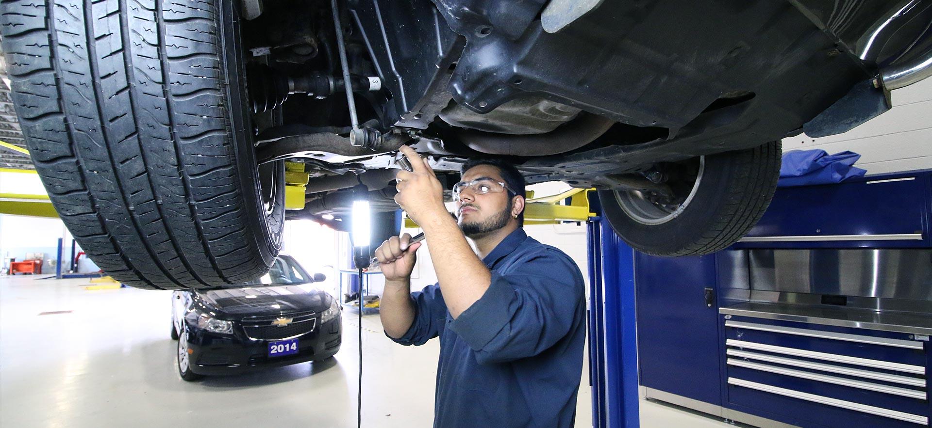 One male Motive Power Fundamentals - Automotive Repair student works a car thats on a lift. 