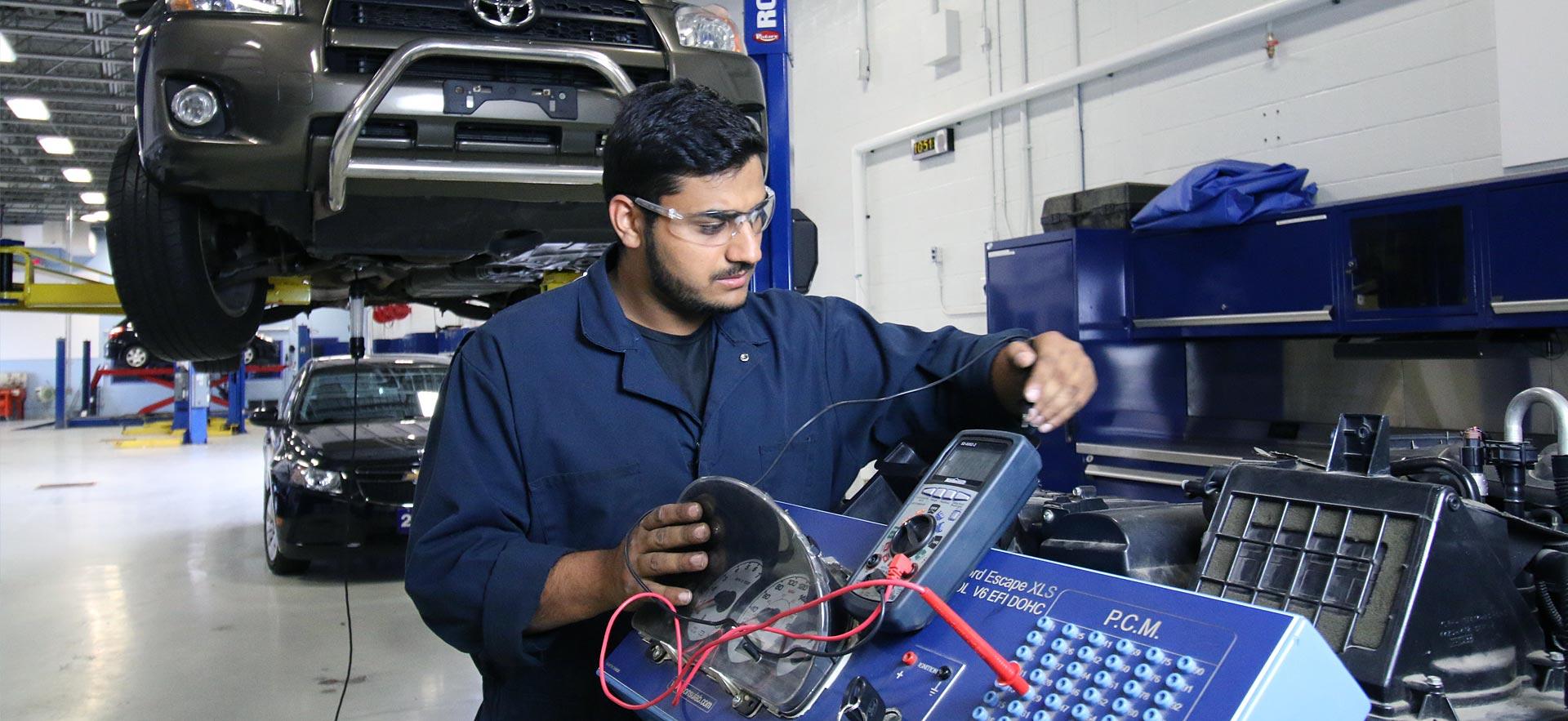 A male Motive Power Fundamentals - Automotive Repair student works on an engine.