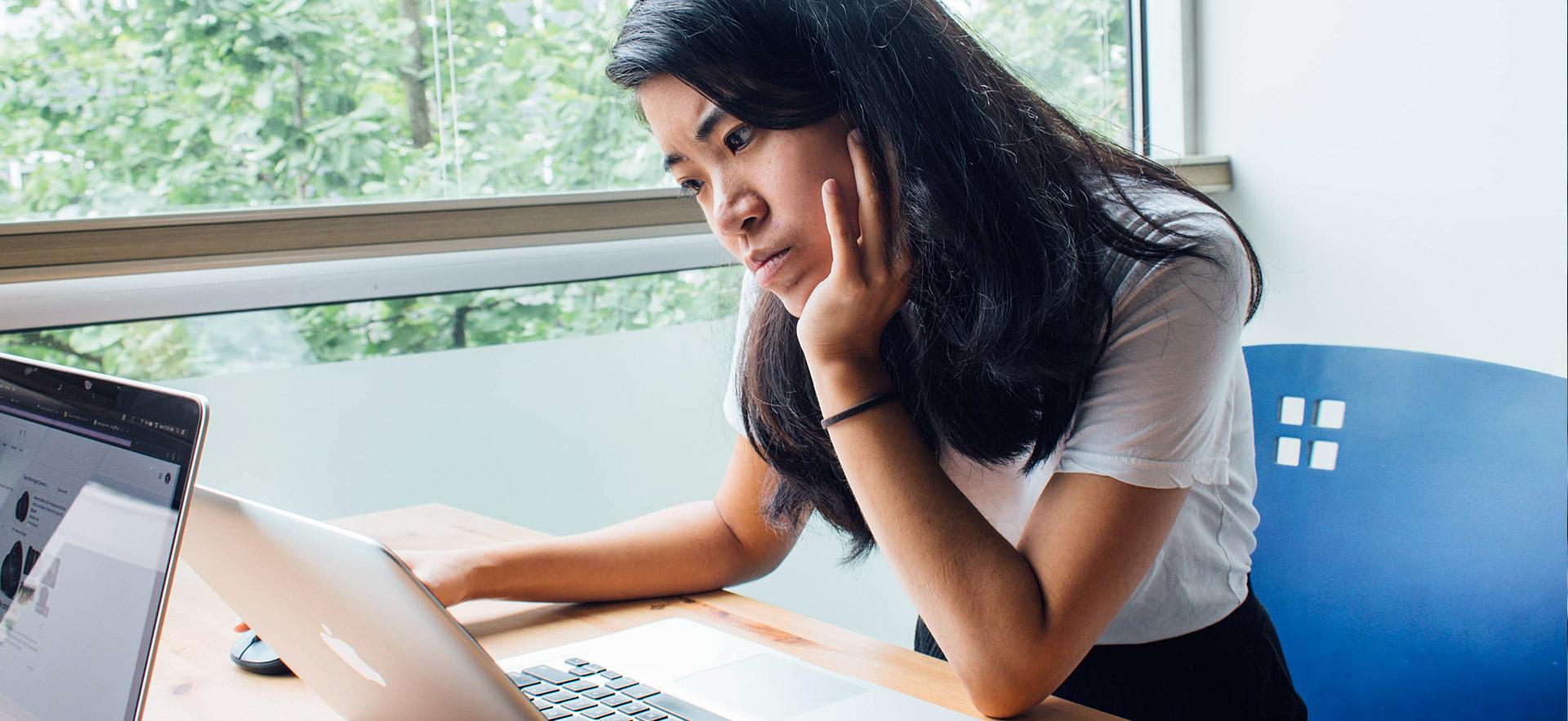 Female student thinking while on computer.