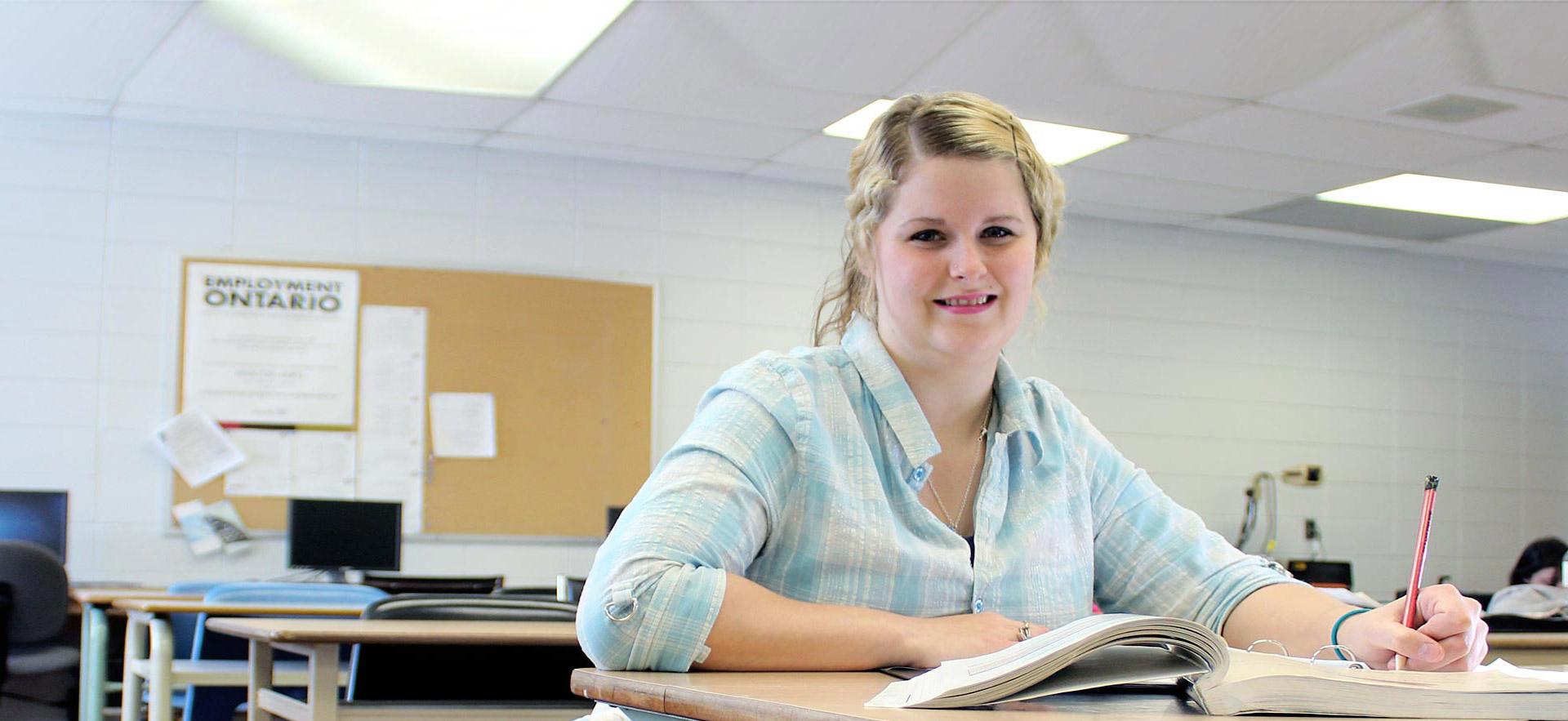 Female student smiling at her desk.