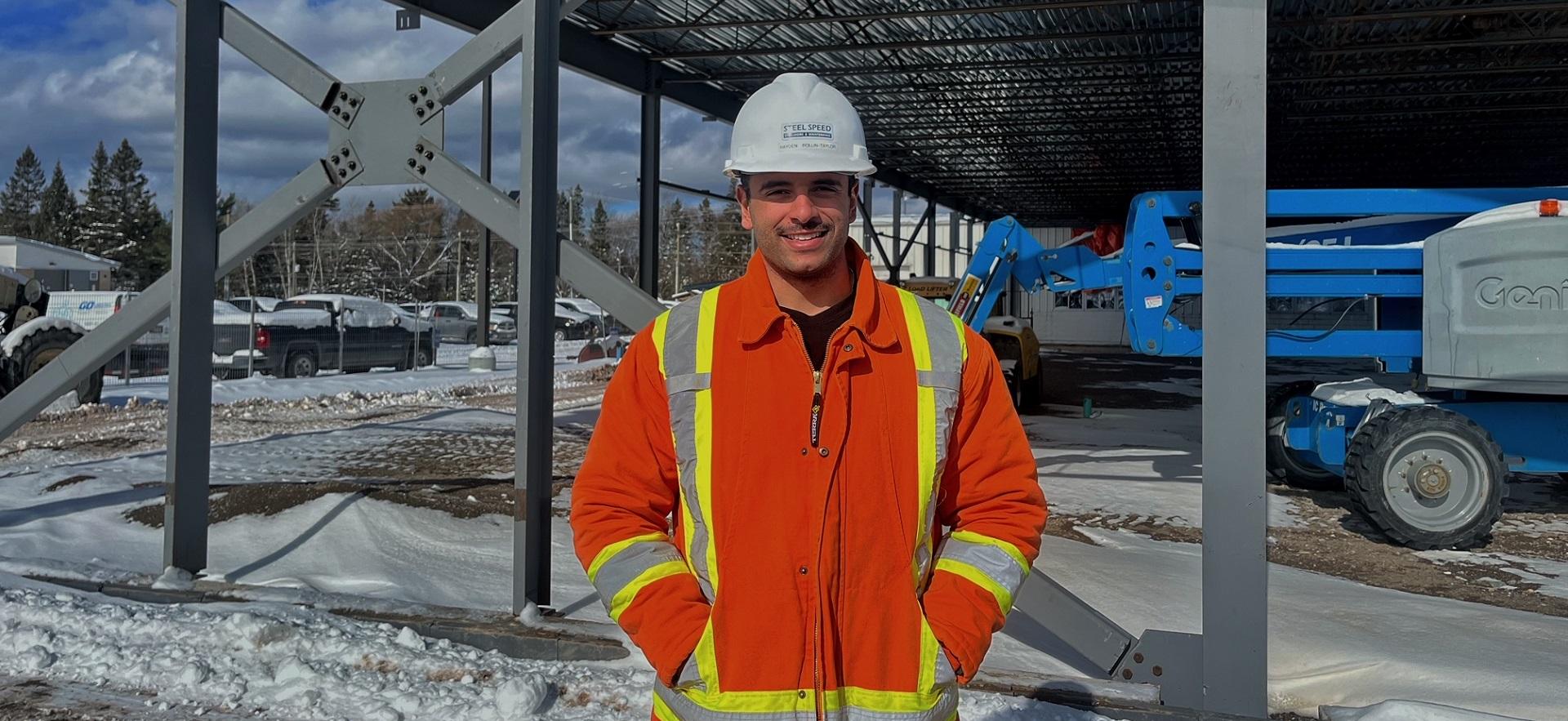 Hayden a Civil Engineering Technician graduate on a worksite with hard hat and safety jacket