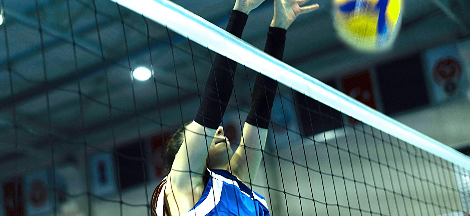 Girl at volleyball net blocking ball