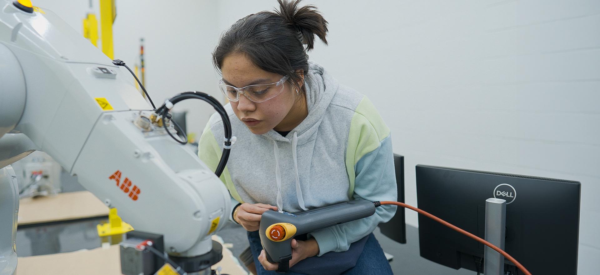 Engineering student working with a robot arms in the robotics lab