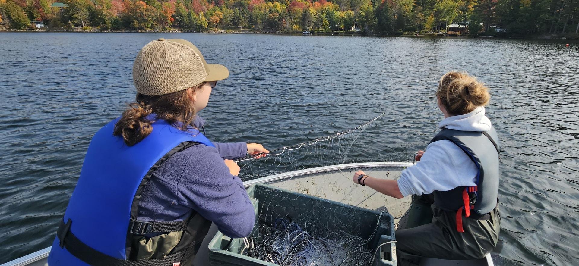 Fish and Wildlife students casting a net on a boat in the lake