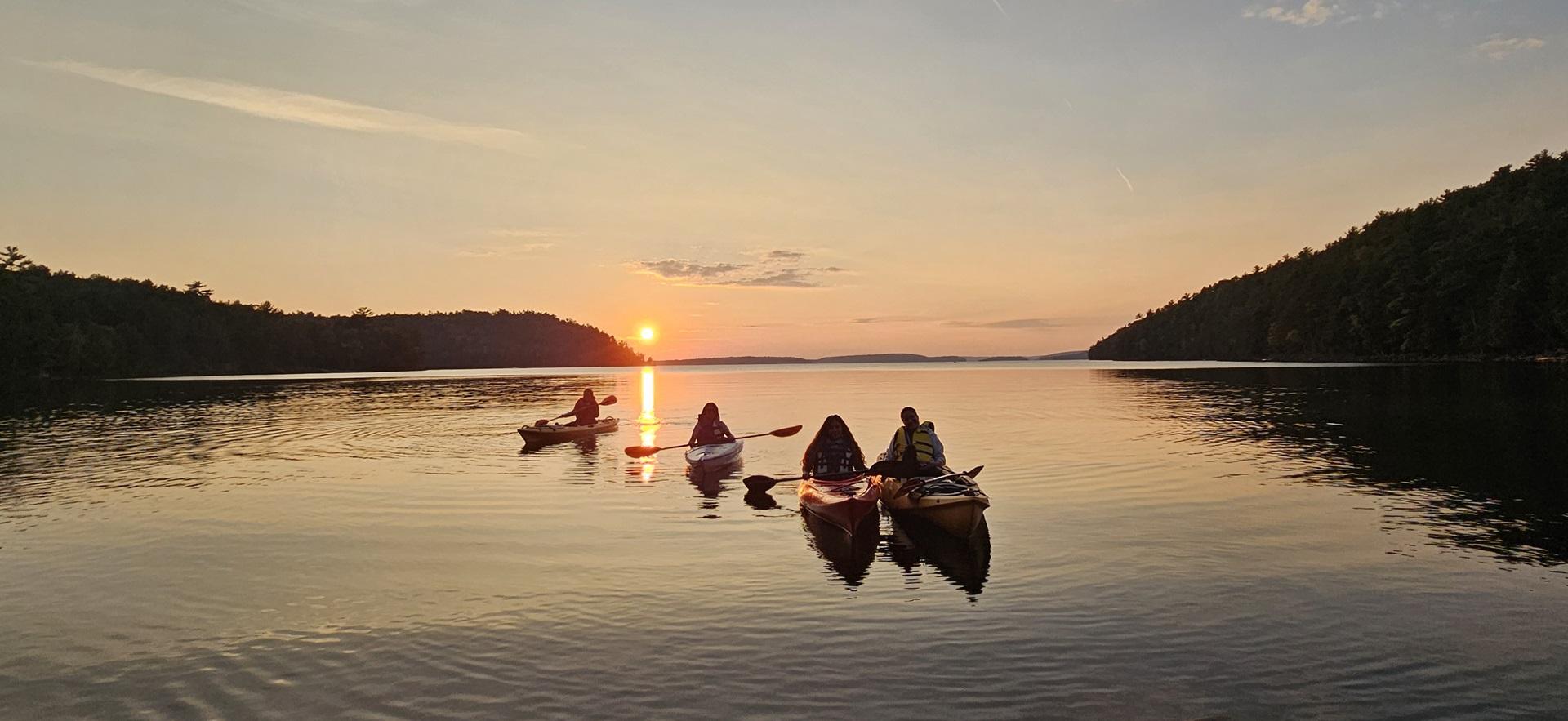 Adventure Rec students in kayaks on the lake during sunset