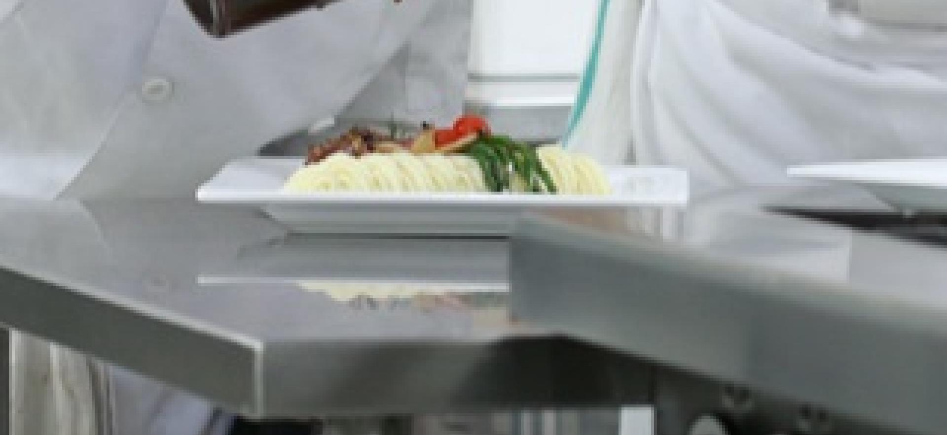 Culinary student prepping a dish with instructor onlooking