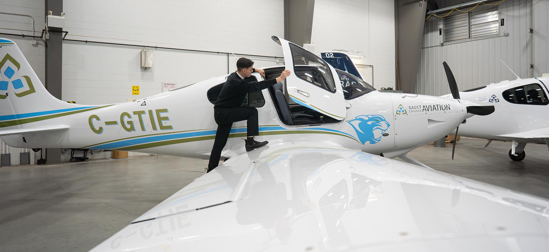 Aviation student standing on wing to get inside Cirrus aircraft