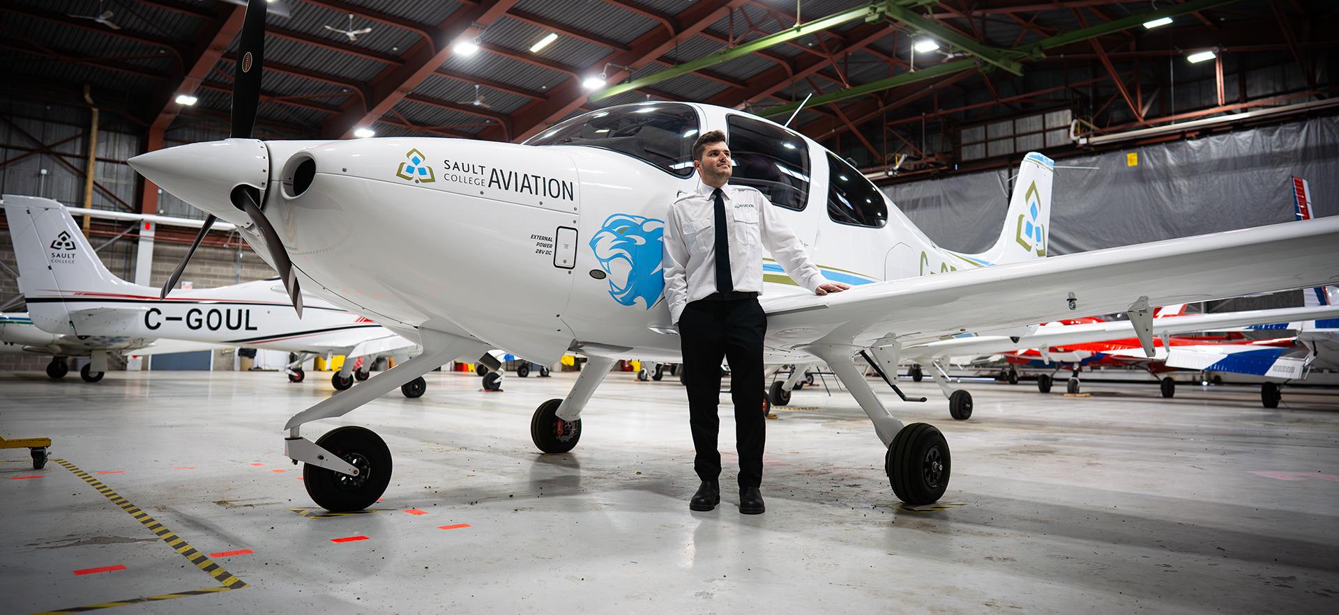 Aviation student posed with plane outside of Hangar