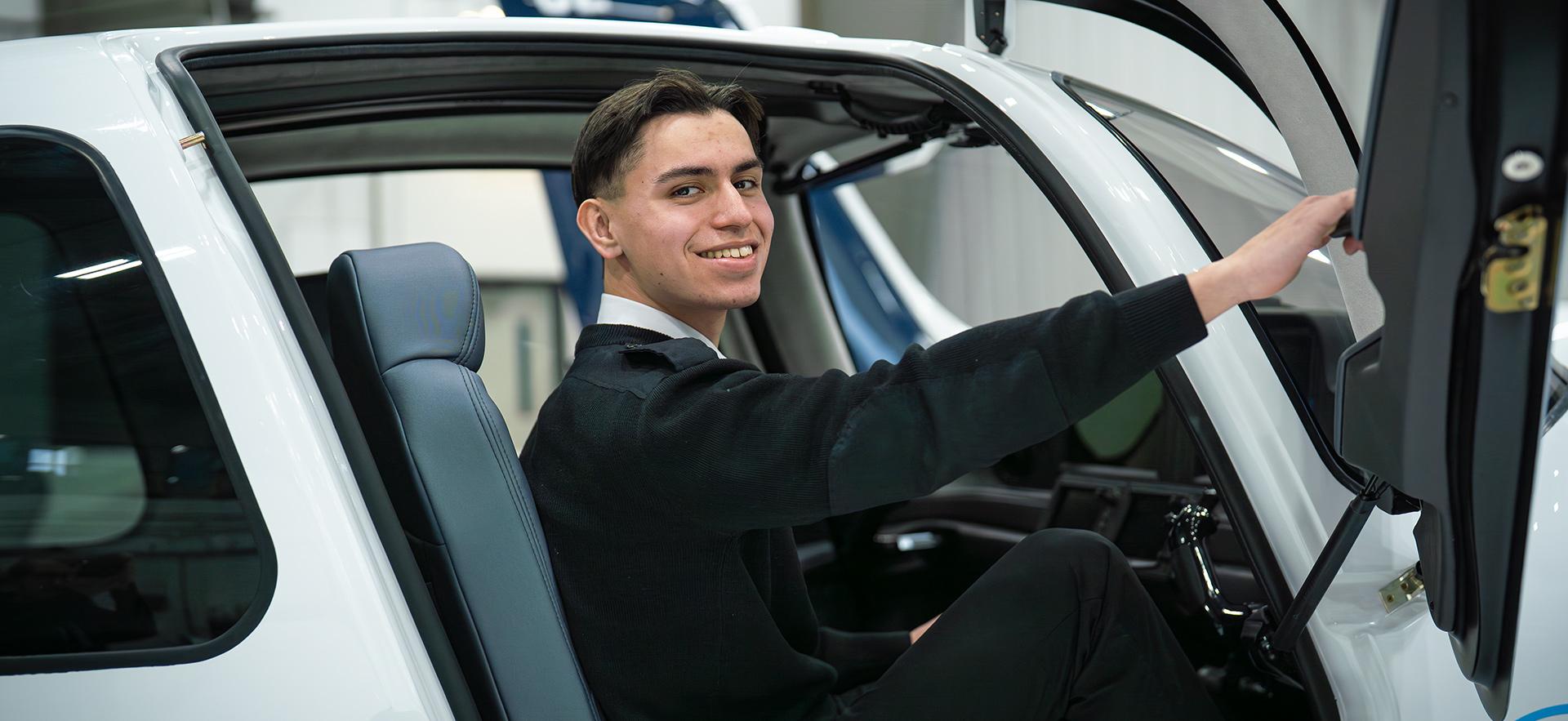 Aviation student sitting in Cirrus aircraft smiling at camera