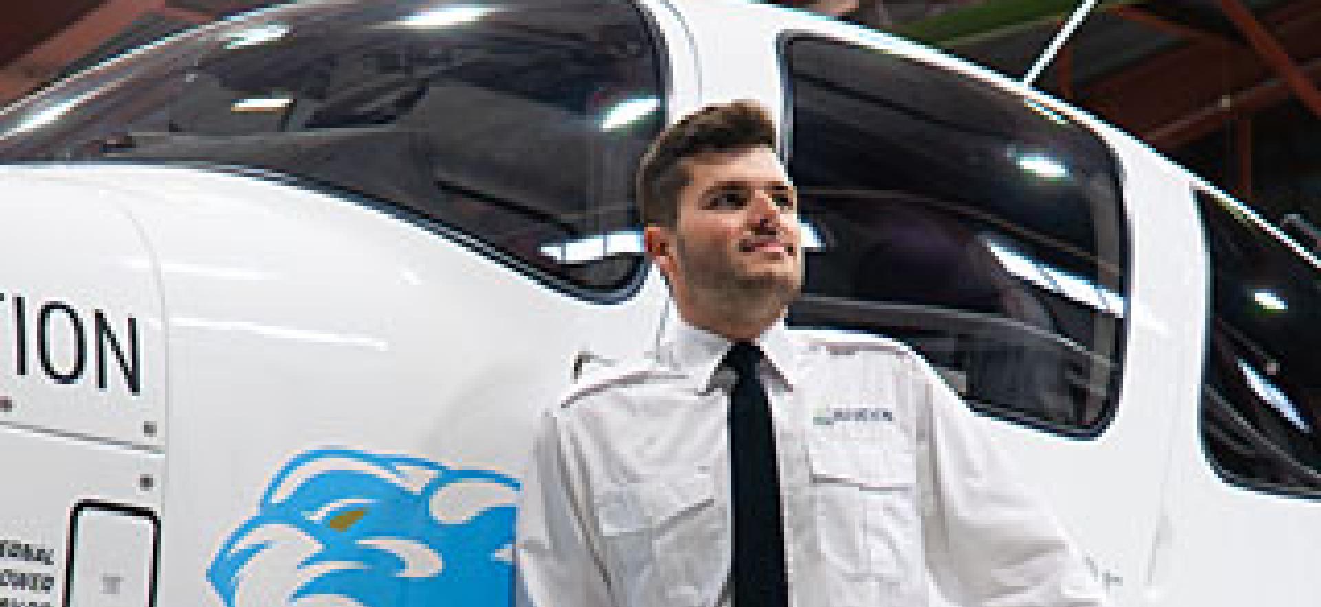 Aviation student standing in front of new Cirrus plane in hangar